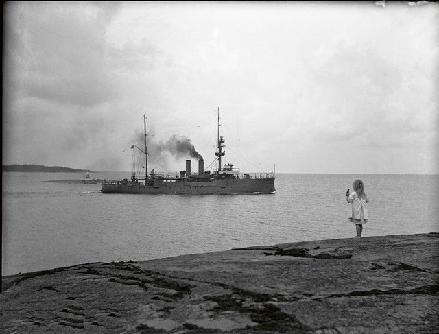 Haapasaarelainen Hilppa-tyttö seuraa venäläisen tykkivene Svutšin matkaa Kotkan Haapasaaren edustalla elokuussa 1912. Venäläiset sota-alukset olivat saaristossa tuttu näky. Kuva: Kymenlaakson museo, kuvaaja: Lauri Haapaniemi